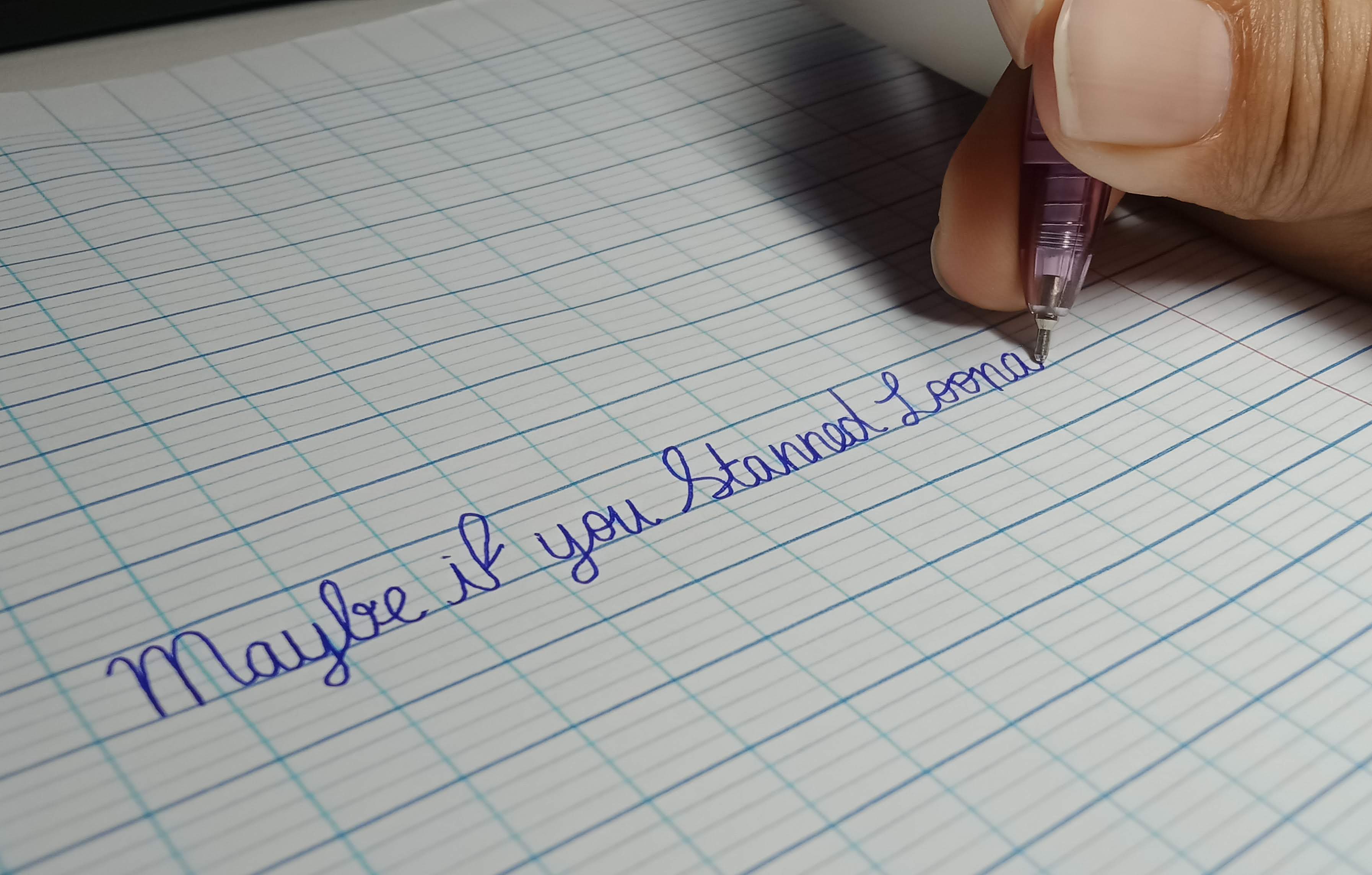 A hand writing flowing cursive letters with a pen