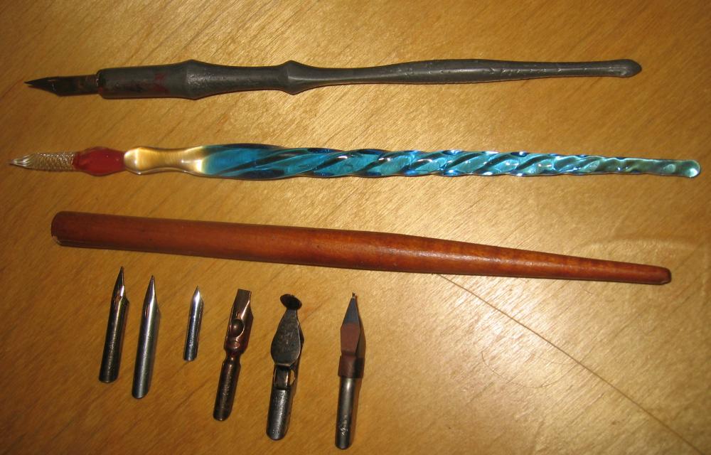 Three dip pen holders with six interchangeable steel nibs laid out on a surface